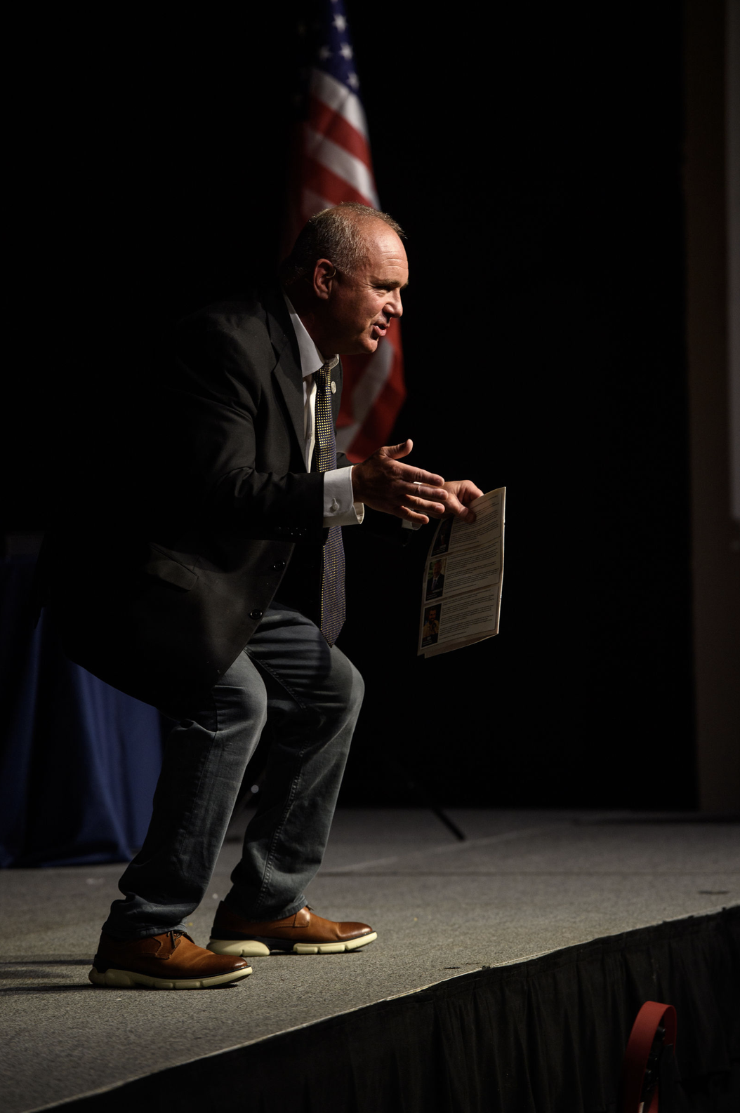Thomas L. Krannawitter engaging an audience while speaking on stage in front of the American flag